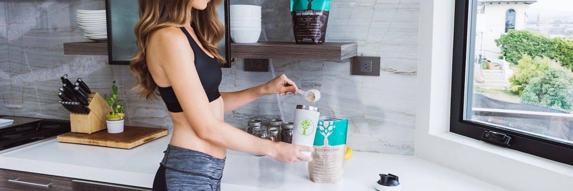 woman in black tank top and blue denim jeans holding clear plastic bottle