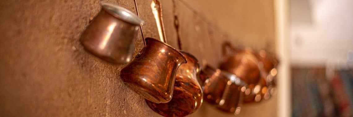 brass-colored cook ware hangs on wall