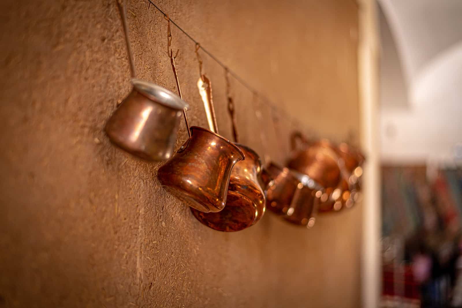 brass-colored cook ware hangs on wall